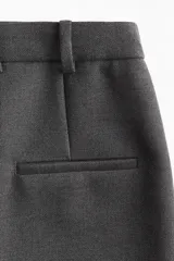 Pollera gris oscuro de corte recto hasta la rodilla, con tajo trasero, tiro alto, pretina prolongada, cierre de corchete oculto y bolsillo trasero decorativo. Sin forrar.