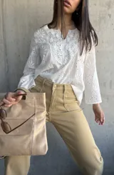Blusa blanca de algodón con bordado broderie, escote en V y mangas largas.