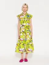Vestido camisero midi color verde lima con estampado de cisnes, flores y elementos abstractos. Tiene cuello camisero, mangas cortas, cierre frontal con botones y lazo en la cintura. La falda es amplia con volantes en el ruedo.