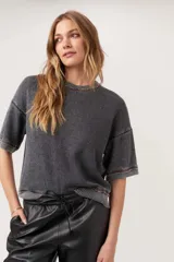 Remera de tejido térmico con lavado burnout, color gris oscuro, de calce boxy y relajado con hombros caídos y mangas al codo. Presenta terminaciones acanaladas en cuello, puños y ruedo.