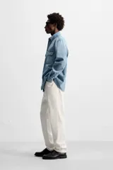 Camisa celeste de denim de algodón, corte relaxed fit, con cuello solapa, manga larga con puños abotonados, dos bolsillos de parche con solapa en el pecho, efecto lavado y cierre frontal abotonado.