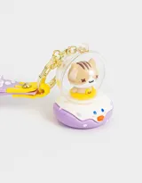 Llavero con dije de gatito dentro de una burbuja con base lila y correa de silicona lila con diseño de letras y dibujos en amarillo y blanco.