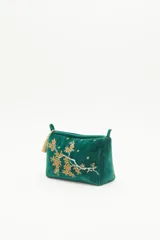 Bolso de mano tipo clutch, color verde esmeralda, de terciopelo con bordado de flores amarillas y blancas. Incluye un cierre superior y un colgante de borla dorada.