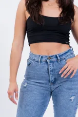 Pantalón de jean celeste con roturas en las rodillas y ruedo doblado.