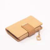 Billetera de cuero sintético color beige con cierre de cremallera y broche con adorno dorado.