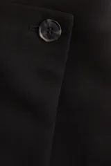 Short pollera mini de viscosa color negro. Diseño cruzado con botón y cierre lateral oculto.