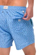 Short de baño celeste con estampado de ballenas en azul y gris. Tiene cintura elástica con cordón ajustable y bolsillos laterales.