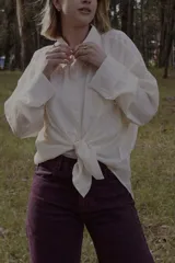 Camisa blanca de mangas largas con cuello clásico y cierre frontal con botones.