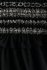Vestido corto negro con cuerpo superior de tejido a rayas horizontales en blanco y negro, falda de popelina con volados y mangas cortas con volados.