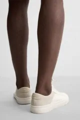 Zapatillas deportivas blancas con detalle de color a contraste en el talón y suela con acabado irregular.