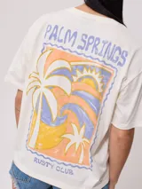 Remera color amarillo claro con estampado en el frente que incluye un sol y el texto 'Rusty Club'. Corte holgado.