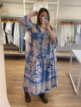 Vestido midi de viscosa azul con estampado floral beige, corte holgado, cuello camisero y mangas largas con puños acampanados.