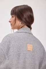 Tapado gris de lana con doble botonadura, cuello con solapas y bolsillos laterales.
