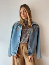 Campera de jean celeste con tachas doradas en forma de estrella en la parte superior de la espalda y los puños.