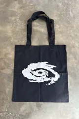 Tote bag negra con diseño gráfico blanco en el centro.