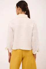 Camisa blanca de lino con cuello clásico y puños con detalle de crochet.