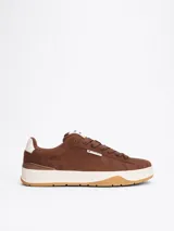 Zapatillas Tommy Jeans de corte bajo, color marrón, confeccionadas en gamuza con interior de poliéster y suela de goma. Presentan cordones, entresuela texturizada, etiqueta de la marca en el lateral y parche en la lengüeta.