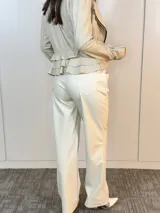 Pantalón de cuero sintético color beige, de corte recto, con bolsillos laterales y botón frontal.