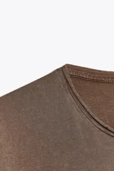 Camiseta marrón de algodón con cuello redondo, corte recto y mangas cortas. Tiene un efecto de lavado que le da un aspecto vintage.