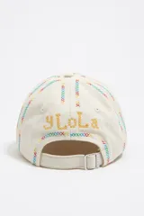Gorra de béisbol color crudo, con bordados multicolores en forma de cruces y la palabra 'Bimba' en el frente.