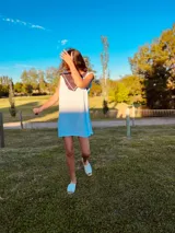 Vestido corto tejido en hilo de algodón color celeste, con cuello y espalda con apliques de cuero artesanal en tonos marrón, blanco y celeste.