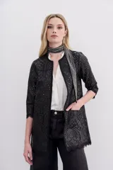 Saco negro de símil cuero con bordado de flores y calado en toda la prenda. Tiene cuello redondo, mangas largas y apertura frontal con broches ocultos.