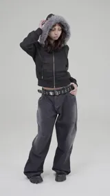 Campera corta negra con capucha y cierre frontal, confeccionada en poliéster. Tiene corte boxy y piel sintética gris alrededor de la capucha.