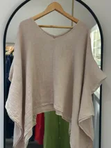 Blusa de manga corta con escote en V, confeccionada en tejido ligero de lino en tono beige claro. Presenta un diseño amplio y asimétrico con caída.