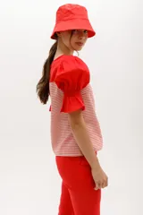 Blusa de rayas horizontales grises y blancas, con mangas abullonadas cortas negras y escote redondo.