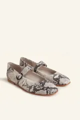 Zapato tipo Mary Jane de charol color borgoña, con punta redondeada, tira sobre el empeine con hebilla y suela de cuero.