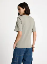 Remera color verde lavado, estilo camiseta, corte asimétrico, cuello redondo, manga corta y detalle fruncido lateral.