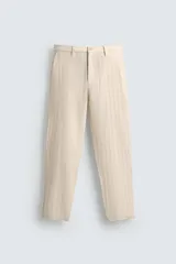 Pantalón chino de corte relajado, color beige claro, con textura de rayas verticales sutiles. Presenta cintura ajustable con cordón interior, bolsillos delanteros y bolsillos traseros de vivo.