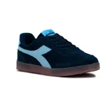 Championes casuales Diadora modelo Bamtelo, de corte bajo, color azul marino con detalles en celeste claro. Presentan un diseño de gamuza con el logo de la marca en el lateral y suela de goma color caramelo.