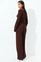 Pantalón marrón de punto con textura arrugada, corte holgado, tiro alto, cintura elástica y piernas rectas.