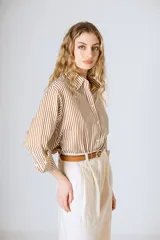 Camisa holgada de manga larga con rayas verticales verdes y blancas. El ruedo es más largo en la parte trasera.