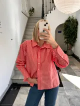 Camisa color coral con rayas verticales blancas, de corte recto y mangas largas con puños abotonados.