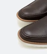Zapato slip on marrón de cuero con suela blanca.