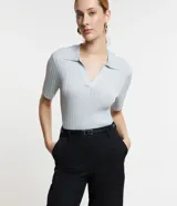 Blusa de viscosa color celeste con cuello polo, mangas cortas, textura acanalada e hilo metalizado.
