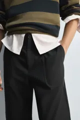 Pantalón negro de corte recto, con bolsillos frontales tipo parche y bolsillos traseros de ojal.