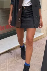 Minifalda negra de cuero sintético con cierre frontal y bolsillos laterales.