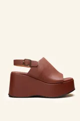 Sandalias con plataforma color marrón, con capellada envolvente, pulsera trasera ajustable y hebilla metálica.