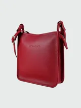 Bandolera Longchamp modelo Le Foulonné, color crudo, con correa fina regulable, cierre superior y logo grabado en el frente.