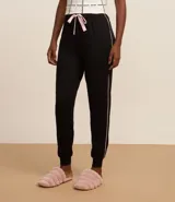 Pantalón de pijama negro con cintura elástica, detalle de lazo rosa y ribete blanco en los laterales.