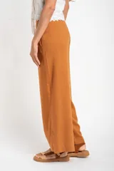 Pantalón de lino color ocre, de corte recto y tiro medio, con lazo de ajuste en la cintura.
