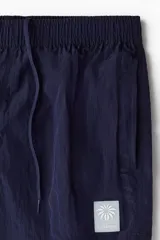 Short de baño azul marino de nylon con elástico revestido y cordón para ajustar oculto en la cintura, bolsillos laterales y bolsillo de solapa con cierre autoadherente atrás. Largo por encima de la rodilla con abertura corta en los laterales y suspensor interior en malla suave.