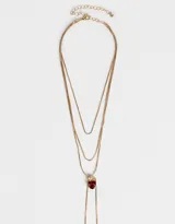 Collar largo multicadena dorada con dije de corazón rojo con strass y cierre de mosquetón.