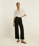 Pantalón de vestir negro de corte recto, con cintura alta y cinturón fino con hebilla metálica.