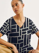 Blusa de cuello en V con estampado geométrico de líneas blancas sobre fondo azul marino.