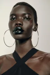 Vestido largo negro de tejido elástico, con escote halter y bajo con flecos a tono.