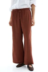 Pantalón marrón de punto texturado, corte holgado, tiro alto, piernas rectas, elástico en la cintura y cordón para ajustar.